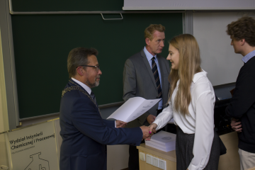 Phograph presents the Dean of the Faculty awarding the female student the matriculation certificate