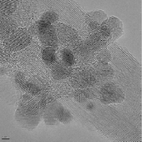 Obraz z transmisyjnego mikroskopu elektronowego w kolorze jasnoszarym i ciemnoszarym. W kolorze ciemnoszarym widoczne są owalne, nieregularne struktury płatków tlenku grafenu.